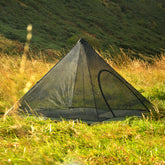 DD Superlight Pyramid Mesh Tent set up in a grassy field, ideal for lightweight backpacking and minimal travel.
